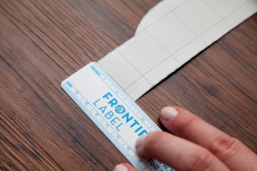Woman measuring the width of a label prototype with a ruler.
