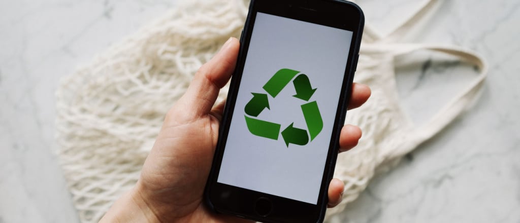 Person holding cell phone with recycling symbol on the screen.