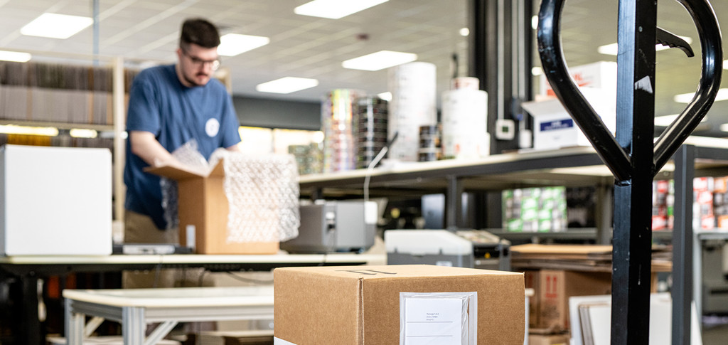Shipping and receiving specialist packs a box for a customer.