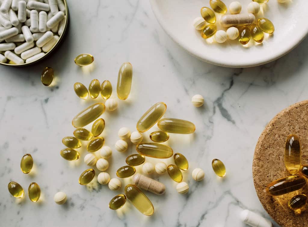 A collection of various vitamins and supplements on a marble countertop.