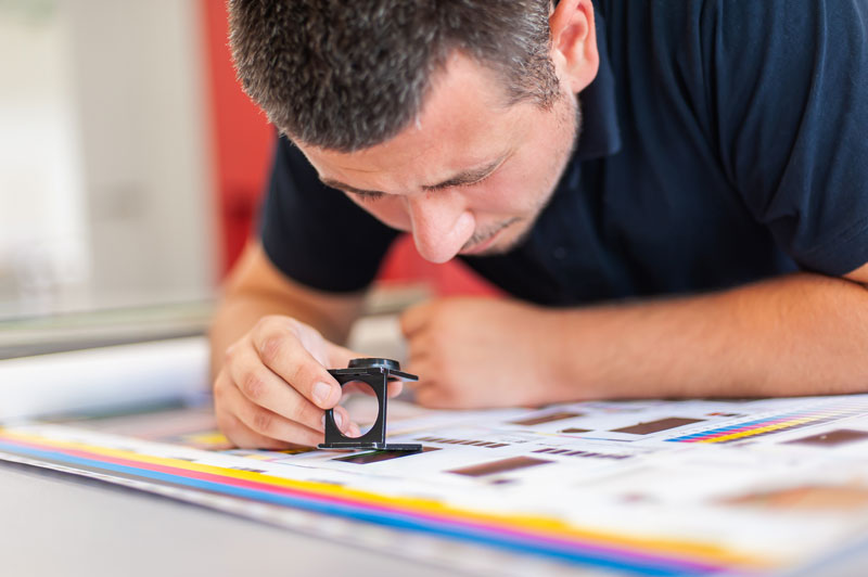 person reviewing printed color using a loop